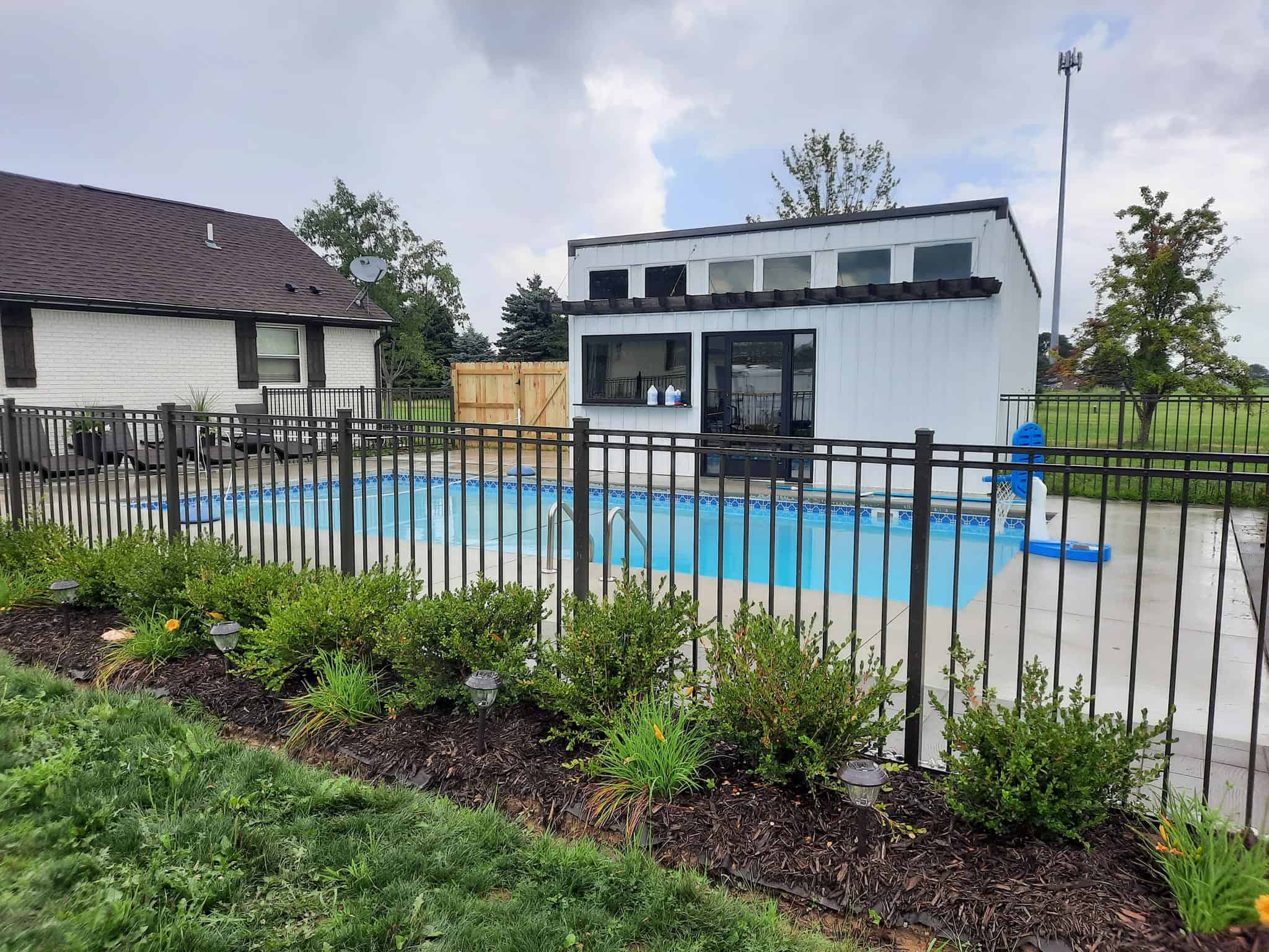 Backyard pool with fence and garden view.