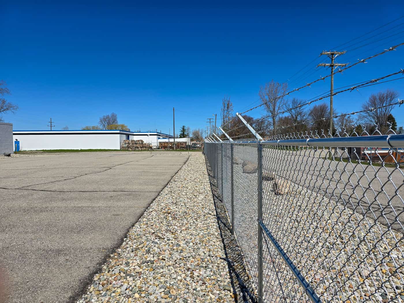 Chain-link fence alongside paved area and blue sky.