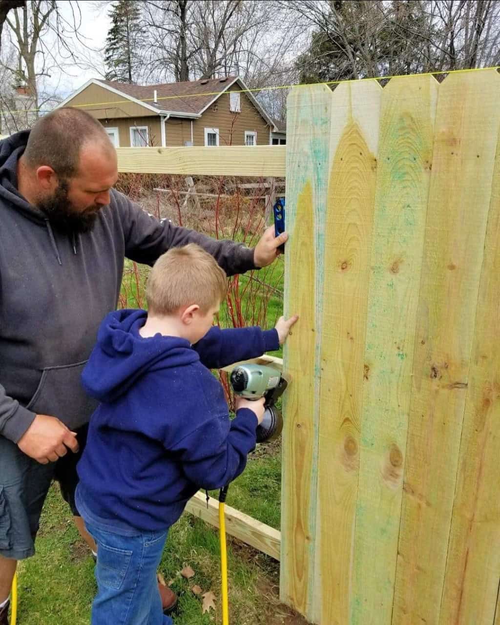 Man and child building a wooden fence together