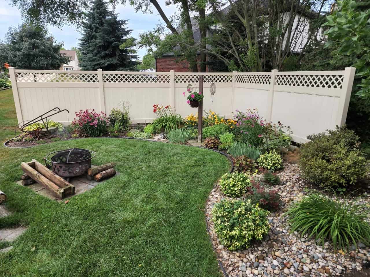 Garden with white fence and fire pit area.